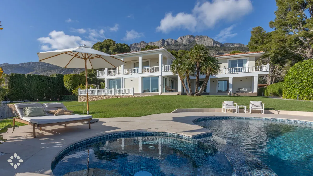 VILLA GOLF's luxurious exterior features a sparkling pool, lush green lawn, and stunning mountain views in Altea, Spain.