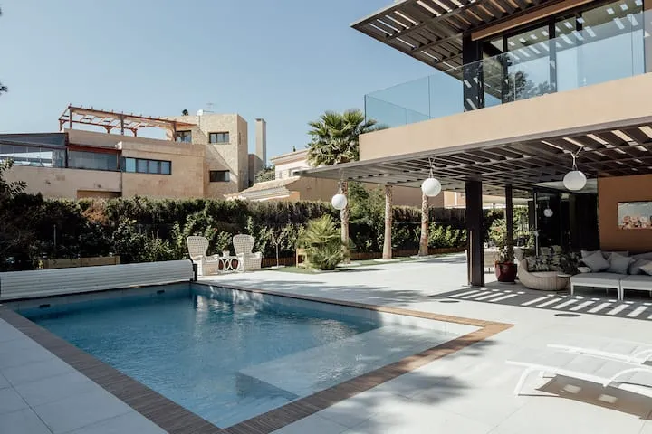 Villa Juana's modern exterior features a private outdoor pool with a cover, sun loungers, and a shaded lounge area in Alicante, Spain.