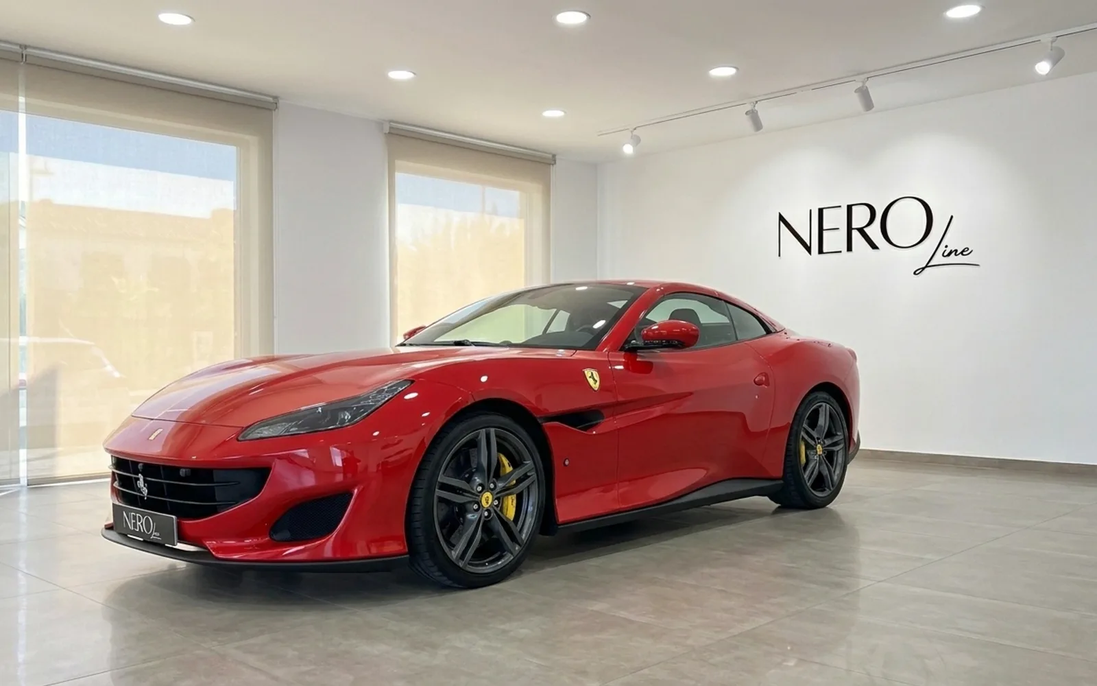 The red Ferrari Portofino convertible is showcased from a front three-quarter angle in an indoor showroom in Madrid.