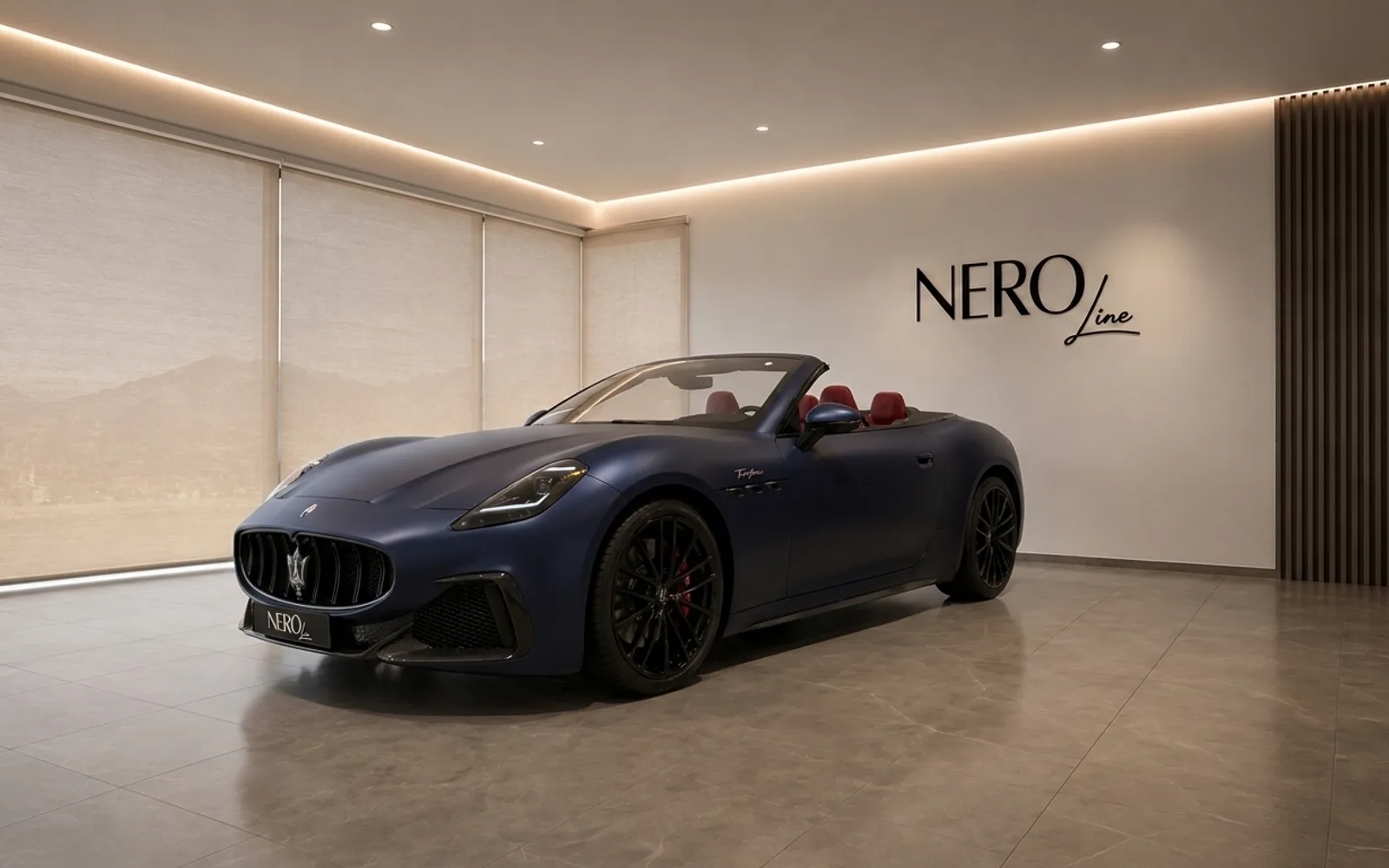 The matte dark blue Maserati GranCabrio convertible is shown from a front three-quarter view in a modern showroom in Lausanne.