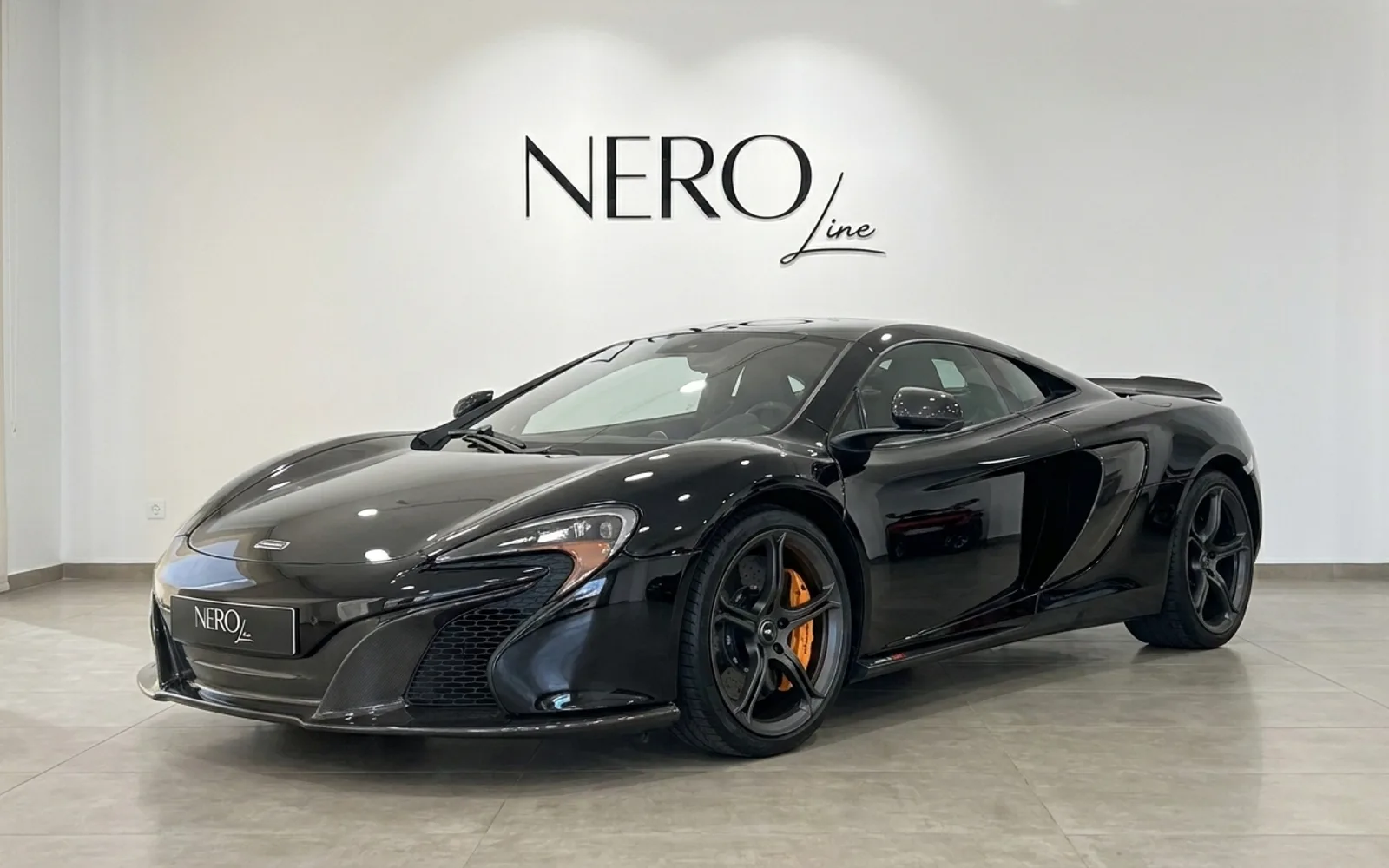 黒いマクラーレン650S MSOスーパーカーがマドリードのショールームに、前方3クォーターアングルで駐車されています。