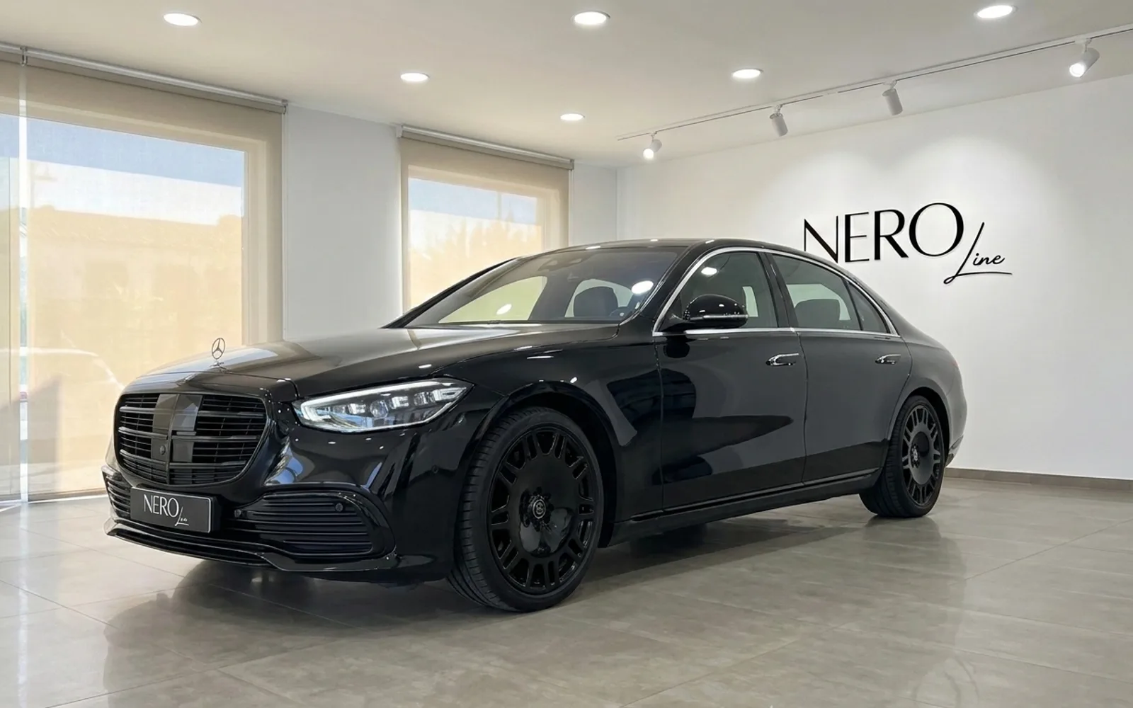 Mercedes-Benz S 450 4MATIC — Showroom in Alicante The gloss black Mercedes-Benz S 450 4MATIC is showcased in a showroom with large windows in Alicante, Spain.
