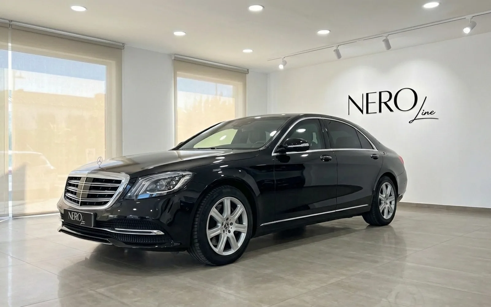 黒いメルセデス・ベンツS 600 L GUARD高級装甲セダンが、マドリードの明るいショールームで前方斜めから展示されています。