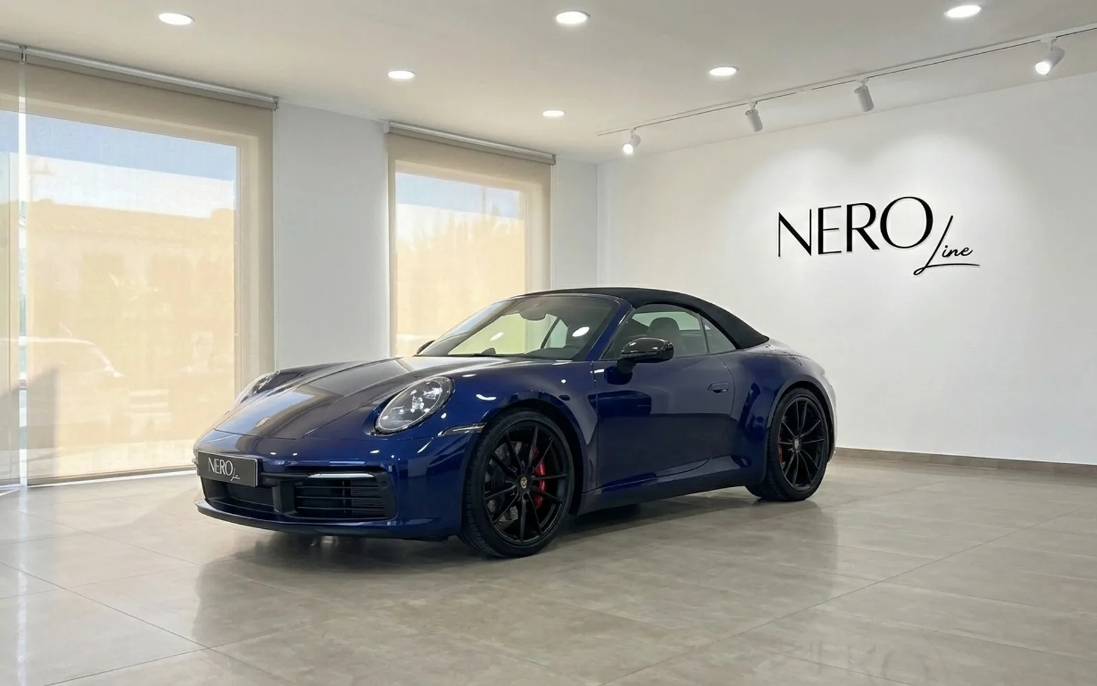 سيارة بورش 911 كاريرا 4S كابريو الزرقاء موديل 2022 متوقفة في الداخل، تعرض تصميمها الأنيق وسقفها القماشي الأسود في إيبيزا.