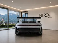 Rear view of the gloss Arctic Grey Porsche GT3 RS in a modern garage overlooking the mountains of Zurich.