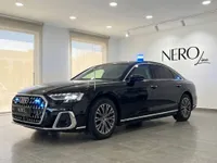 The black Audi A8 L VR10 Armoured car is parked in a modern showroom in Madrid, featuring a blue emergency light on its roof.