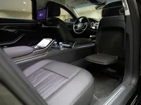 The luxurious rear interior of the Audi A8 L VR10 Armoured car in Madrid, featuring comfortable seats, a central console, and an entertainment screen.