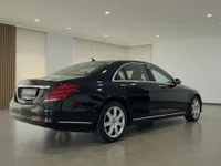 The Mercedes-Benz S 600 L GUARD in gloss black is shown from a rear three-quarter angle in a showroom in Zurich.