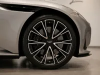 Close-up of the metallic silver Aston Martin DB12's front wheel and fender, highlighting the intricate alloy rim in Lausanne.