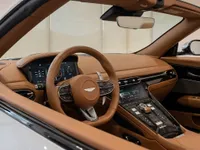 The luxurious tan leather cockpit of the Aston Martin DB12 Volante, showcasing the steering wheel and dashboard in Lausanne.