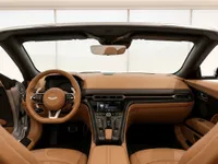 The luxurious tan leather interior of the Aston Martin DB12 Volante in Lausanne, showcasing the dashboard, steering wheel, and center console.