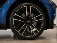 The Aston Martin DBX707's front wheel, featuring stylish multi-spoke black and silver rims, and a section of its blue fender in Lausanne.