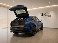 Aston Martin DBX707 in gloss Ion Blue, showcasing its spacious open trunk from the rear in Lausanne.