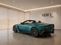 The Metallic Teal Aston Martin Vantage Roadster, with its top down, is showcased from a rear three-quarter view in a modern Lausanne showroom.