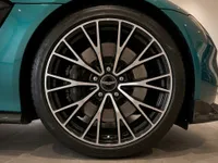 Close-up of the Aston Martin Vantage's front wheel, showing its multi-spoke design and metallic teal fender in Lausanne.