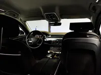 The luxurious interior of the Audi A8 L VR10 Armoured car in Madrid, showing the cockpit, steering wheel, and infotainment screen from the rear passenger seat.