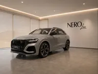 The silver 2022 Audi RS Q8, a performance SUV, is showcased from a front three-quarter angle in a modern Lausanne showroom.