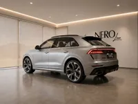 The silver 2022 Audi RS Q8 is showcased in a modern showroom with the Nero Line logo in Lausanne, seen from a rear three-quarter angle.