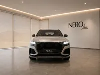 The silver 2022 Audi RS Q8 performance SUV is prominently displayed from the front in a showroom in Lausanne.