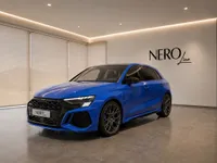 The gloss blue 2023 Audi RS3 Performance Edition is showcased from a front three-quarter view in a modern showroom in Zurich.