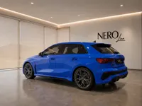The Gloss Blue 2023 Audi RS3 Performance Edition is shown from a rear three-quarter angle in a modern Zurich showroom.