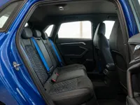 The rear interior of the 2023 Audi RS3 Performance Edition in Gloss Blue, featuring black leather seats with blue stitching and seatbelts in Zurich.