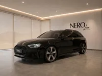 The black 2024 Audi RS4 Avant is showcased in a modern showroom with the Nero Line logo in Zurich.