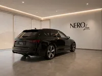 The sleek black Audi RS4 Avant 25 Years Edition is showcased from a rear three-quarter angle in a modern NEROline showroom in Zurich.