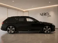 The black 2024 Audi RS4 Avant is showcased in side profile within a luxury showroom in Zurich.