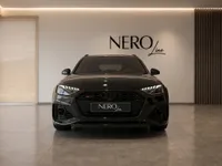 The sleek gloss black 2024 Audi RS4 Avant 25 Years Edition is prominently displayed in a modern showroom in Zurich.