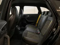 Rear interior of the 2024 Audi RS4 in Zurich, showcasing black leather seats with yellow honeycomb stitching and yellow seatbelts.