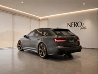 The dark metallic grey Audi RS6 Avant Performance, with its distinctive bronze wheels, is parked in a showroom in Lausanne.