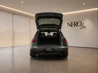The rear view of the 2023 Audi RS6 Avant Performance in gloss dark metallic grey with its trunk open, showcasing its spacious cargo area in Lausanne.