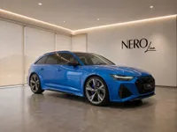 The blue Audi RS6 Avant Performance is showcased in a modern Zurich showroom, featuring its front three-quarter view and sleek design.
