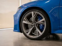The front wheel of a blue Audi RS6 Avant Performance with multi-spoke alloy rim and blue brake caliper, in Zurich.