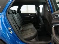 The luxurious rear interior of the Audi RS6 Avant in Zurich, featuring black leather seats with distinctive yellow stitching and an open door.