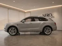 A gloss silver Bentley Bentayga V8 is parked sideways in a modern showroom with the NERO line logo on the wall in Lausanne.
