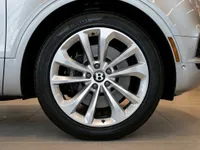 Close-up of the Gloss Silver Bentley Bentayga's front wheel and tire, showcasing its elegant multi-spoke design in Lausanne.