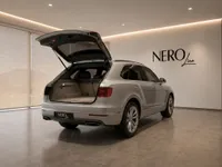 The silver Bentley Bentayga V8 is shown from the rear with its trunk open, parked in a showroom in Lausanne.