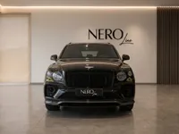 The front view of a sleek black Bentley Bentayga V8 luxury SUV, parked in a modern NEROline showroom in Zurich.