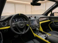 The luxurious interior of the 2021 Bentley Bentayga V8 in Zurich, featuring a black and yellow dashboard, steering wheel, and quilted leather seats.