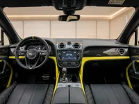 The luxurious black and yellow interior of the Bentley Bentayga V8, featuring the dashboard, steering wheel, and quilted leather seats in Zurich.