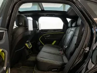 The luxurious rear interior of the Bentley Bentayga V8 in Zurich, featuring black leather seats with lime green stitching and a panoramic sunroof.