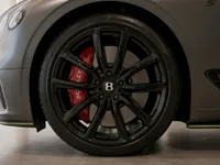 The Bentley Continental GT's front wheel with black multi-spoke rim and red brake caliper is visible in Lausanne.