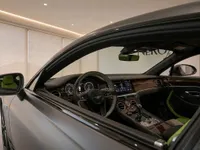 The luxurious interior of the Bentley Continental GT in Lausanne, showcasing the dashboard, steering wheel, and vibrant green and black seats.