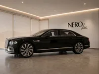 The black 2023 Bentley Flying Spur luxury sedan is showcased in a modern NEROline showroom, viewed from its elegant side profile in Lausanne.