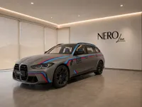 The matte grey BMW M3 Competition Touring with racing stripes is showcased in a showroom in Zurich.