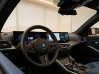 The luxurious cockpit interior of the 2023 BMW M3 Competition Touring in Zurich, showcasing the steering wheel, digital displays, and blue leather seats.