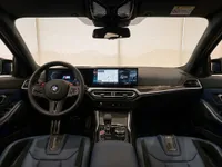 The luxurious interior of the BMW M3 Competition Touring in Zurich, featuring the steering wheel, digital dashboard, infotainment system, and blue leather seats.