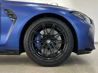 La rueda delantera, la llanta negra multirradio y la pinza de freno azul del BMW M4 Competition Cabrio azul Frozen Portimao mate se muestran en Ibiza.